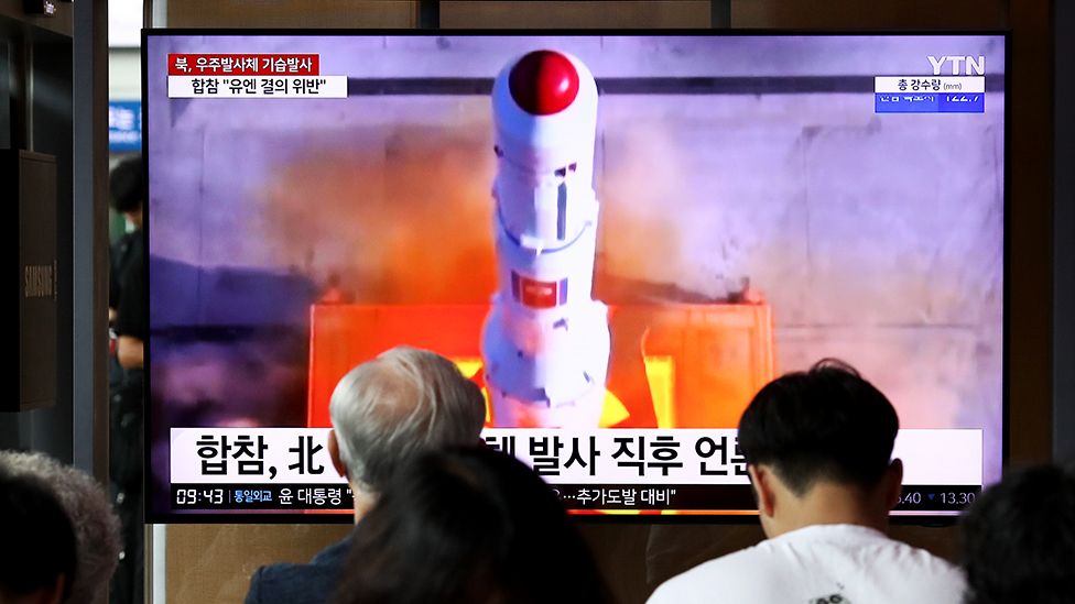 People watch a screen showing the launch from a station in Seoul
