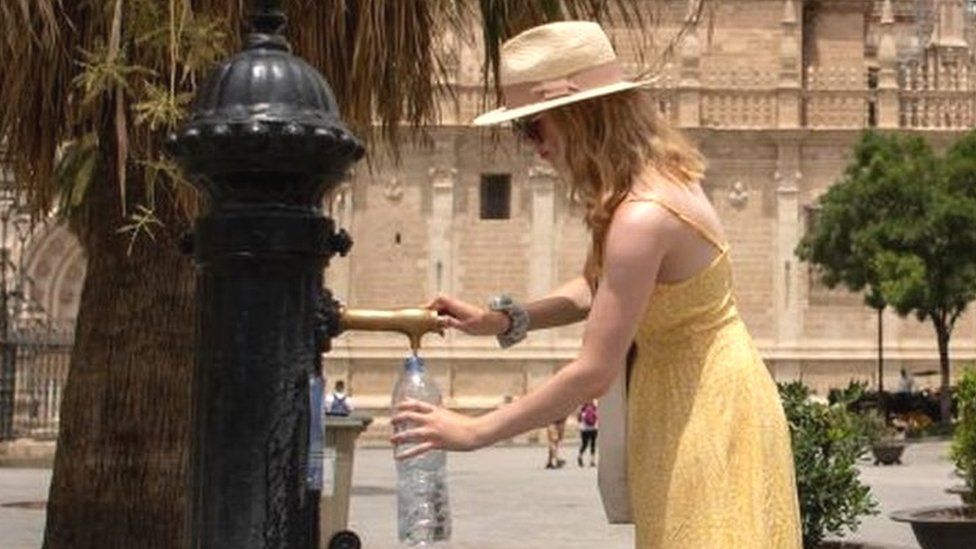A woman fills a bottle of water during a heatwave in Seville on July 12, 2022
