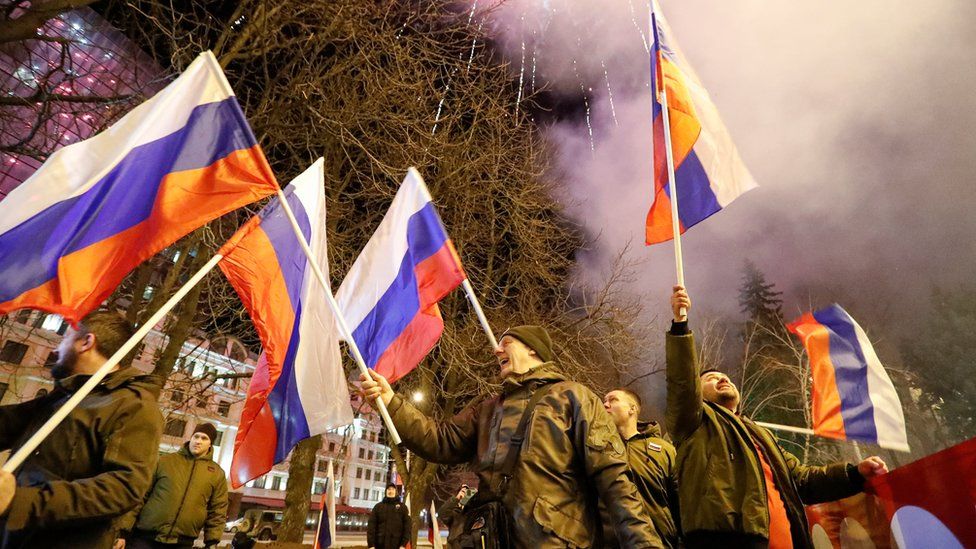 Pro-Russian activists react in a street as fireworks explode in the sky, after Russian President Vladimir Putin signed a decree recognising two Russian-backed breakaway regions in eastern Ukraine as independent entities, in the separatist-controlled city of Donetsk,