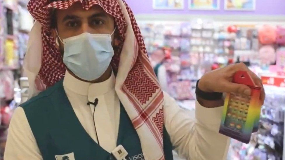 A Saudi ministry of commerce official holds up a rainbow-coloured item confiscated for containing "symbols and signs calling for deviation" and "contradicting common sense" (14 June 2022)