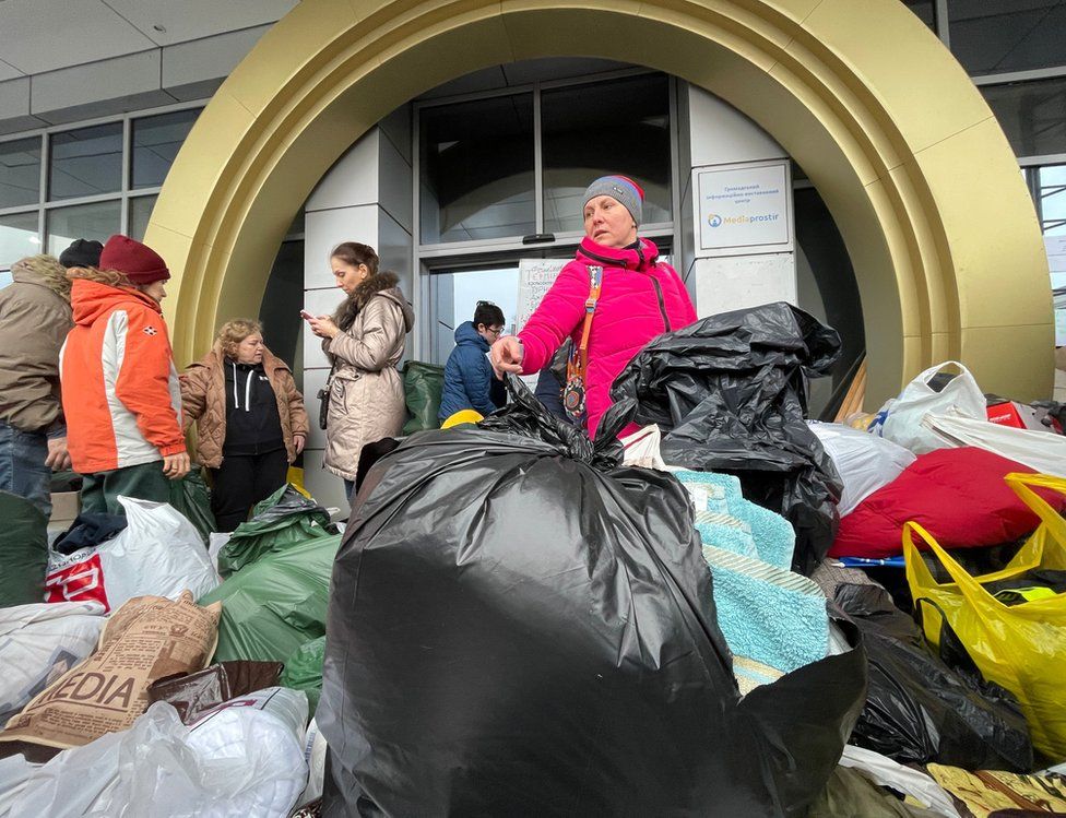 A huge pile of bags - full of donations - sits in the foreground ahead of several female volunteers in warm clothes