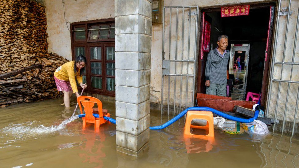 Residents pump flood water out of their house