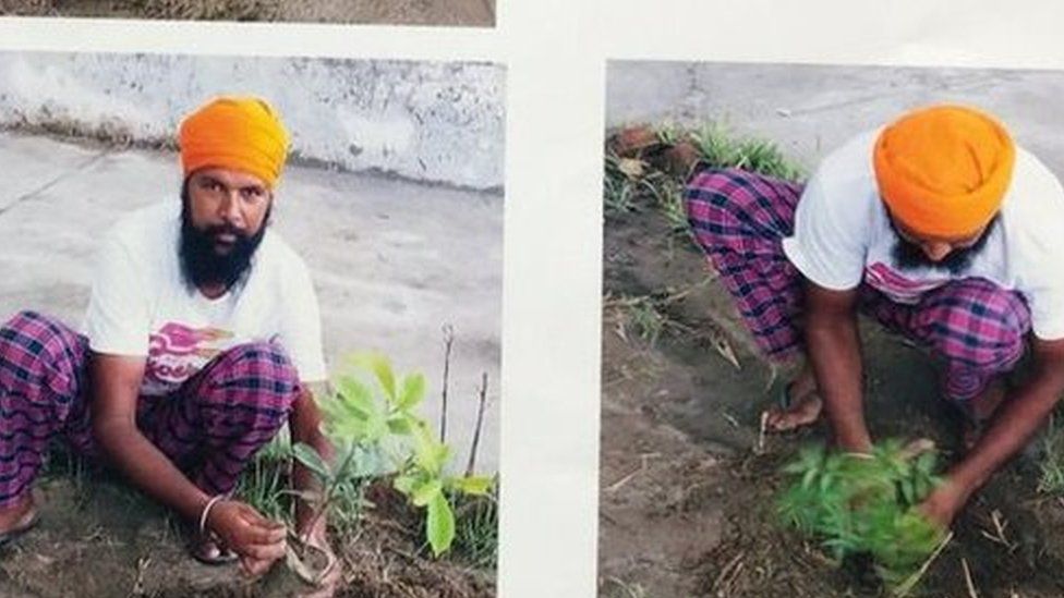 A man poses with plant saplings before applying for a gun license