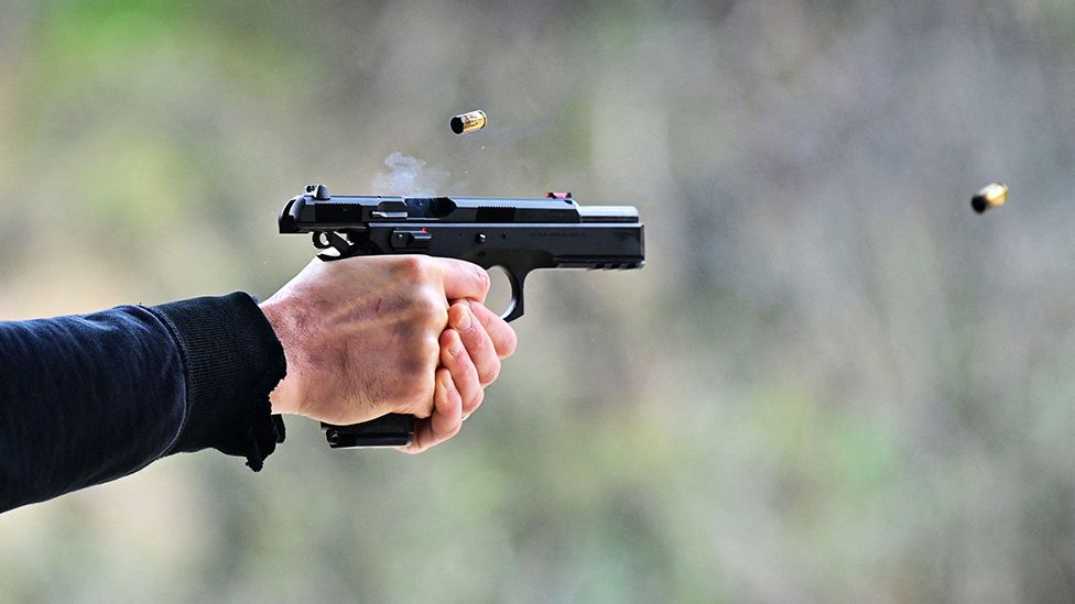 A man fires a pistol at a shooting park in California