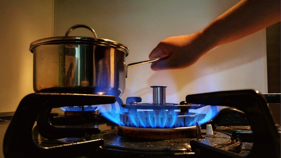 Person holds pot over gas hob