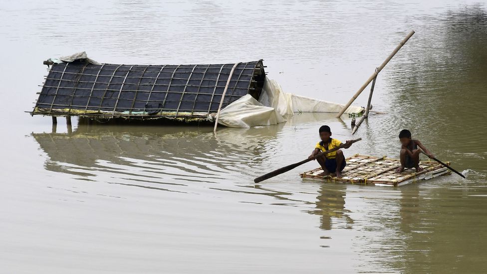 Indian villagers move to a safe place with the help of a boat in a flood-affected area of Assam