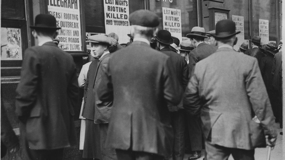 People gather outside the Belfast Telegraph offices to check through lists of those killed during rioting in 1920