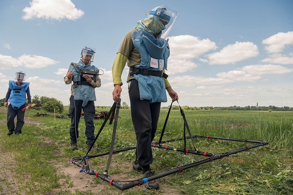 Deminers demonstrate searching for explosive devices using an Ebinger large loop metal detector, outside the town of Ichnia, Ukraine on 7 June 2022