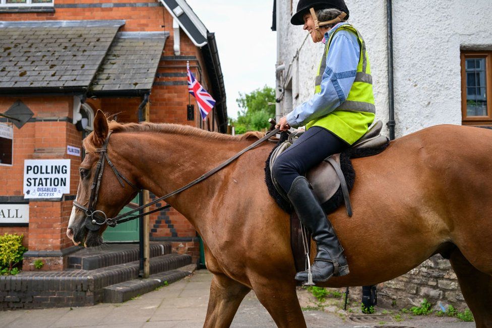 Woman passes polling station on horseback in Uffculme, Devon