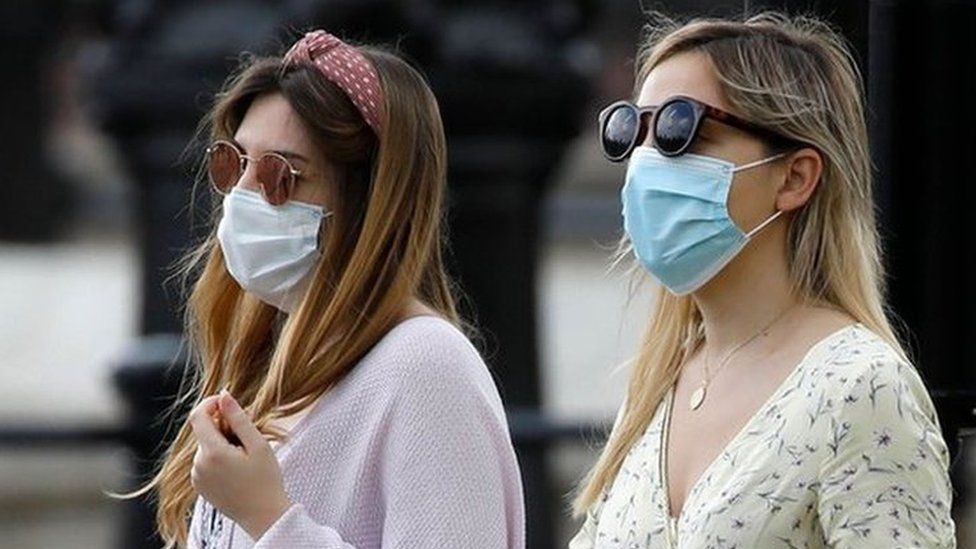 Two women walking wearing face masks