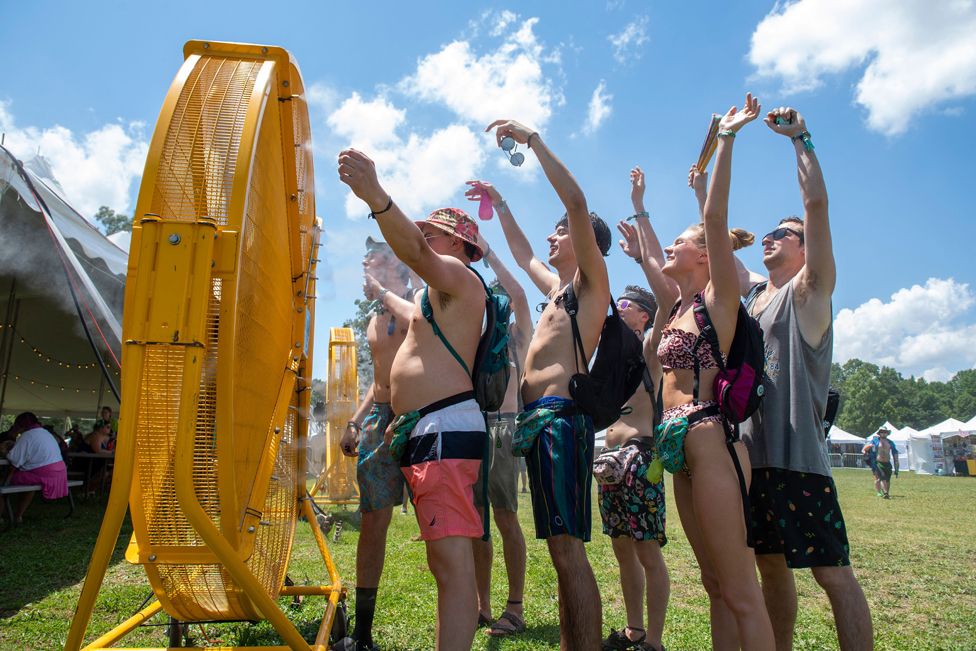 Festival goers attending the Bonnaroo Music and Arts Festival stand in front of giant fans n an attempt to stay cool in 100-degree heat on 17 June 12022 in Manchester, Tennessee.