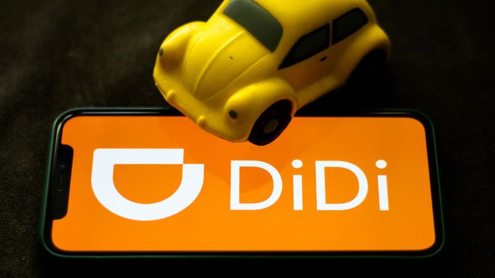 Didi logo on smartphone screen with toy car.