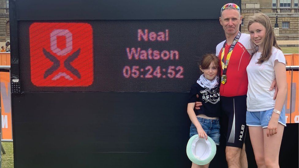 Neal Watson and his two daughters near the time board showing he completed the Outlaw Half Holkham in five hours, 24 minutes and 52 seconds