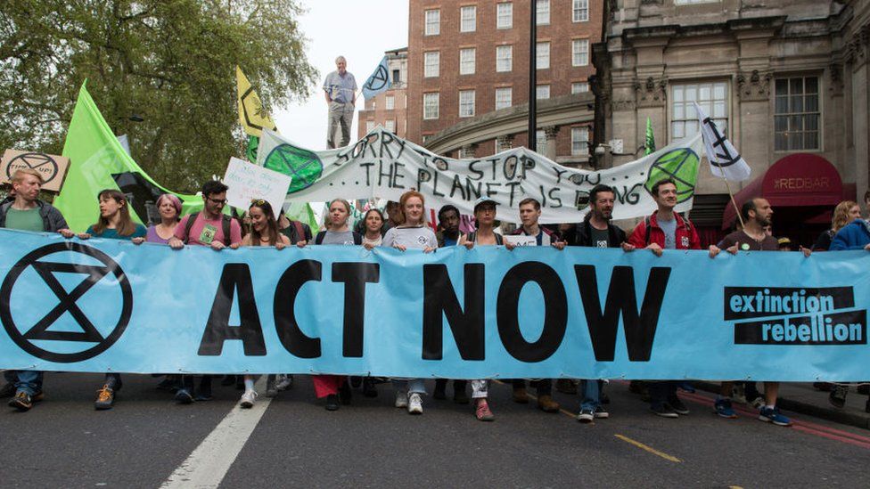 Extinction Rebellion holding a banner saying "Act Now"