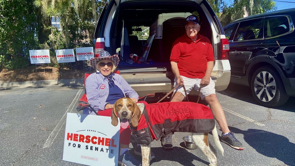 Two voters with Herschel Walker signs