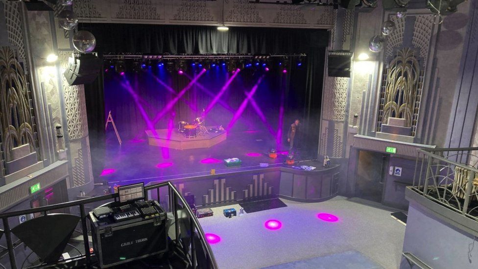 Image of The Wells Picture House interior. The stage is lit up with purple spotlights