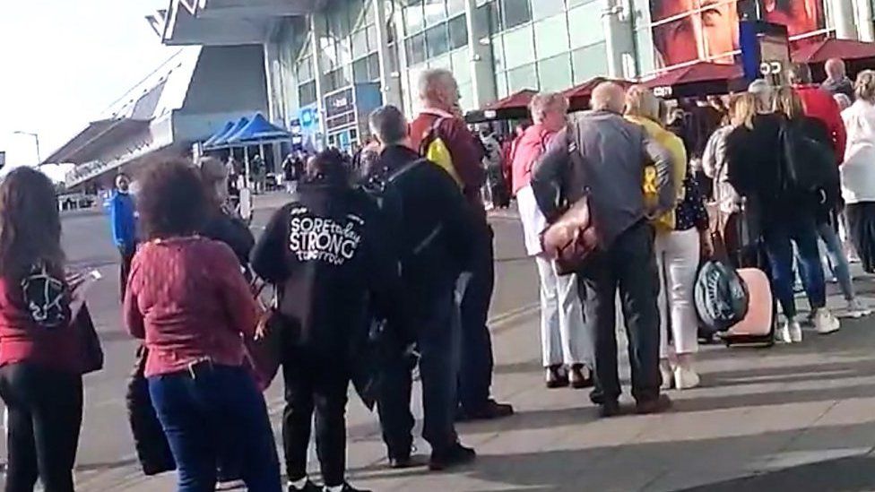 Travellers queuing outside airport