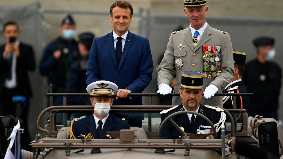 French President Emmanuel Macron and General Francois Lecointre Chief of Staff of the Armed Forces arrive on the command car during Bastille Day Military parade on July 14, 2021 in Paris, France