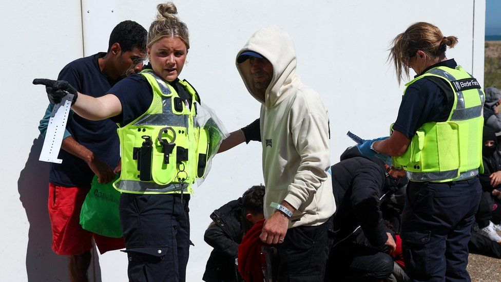 Border Force officers assist people, who are believed to be migrants, in Dungeness, Britain,