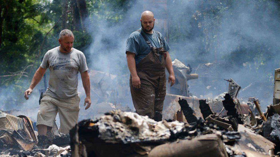 Men look at the remnants of a house which was torn off its foundation and burned after severe flooding in West Virginia on 24 June