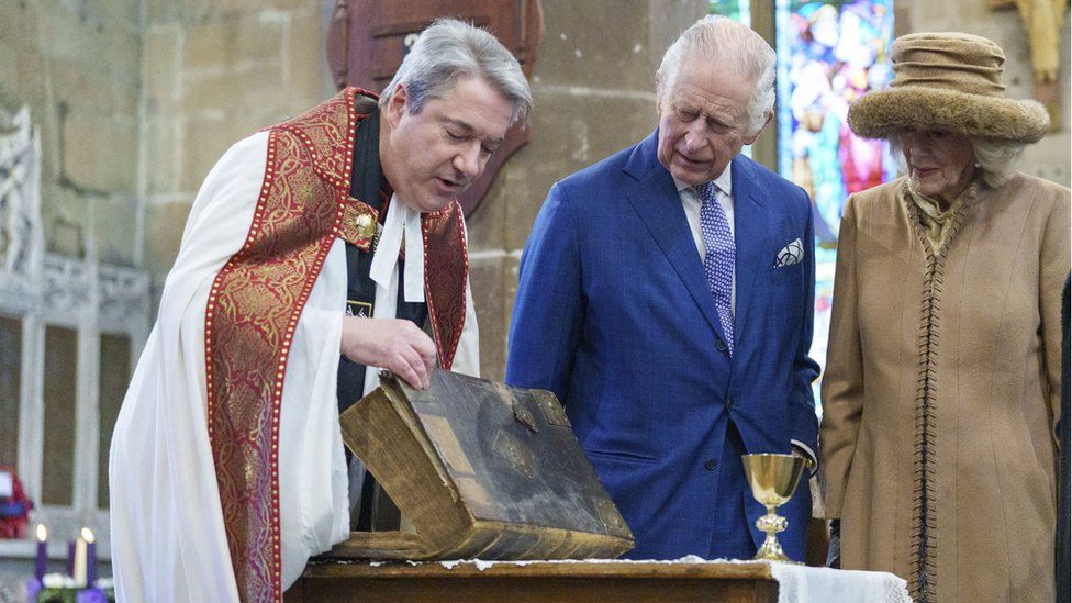 King Charles III and the Queen Consort are shown a first edition King James Bible and a rare early 14th century chalice by the Rev'd Canon Dr Jason Bray following a celebration at St Giles' Church to mark Wrexham becoming a City. Picture date: Friday December 9, 2022. PA Photo. See PA story ROYAL King. Photo credit should read: Dominic Lipinski/PA Wire