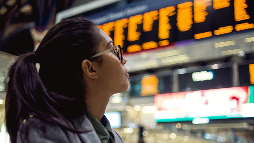 A woman looks up at a train times board