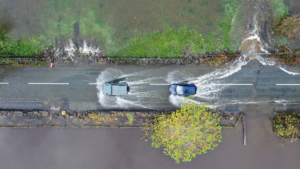 Cars driving on a flooded road as the River Conwy bursts its banks in Llanrwst last October