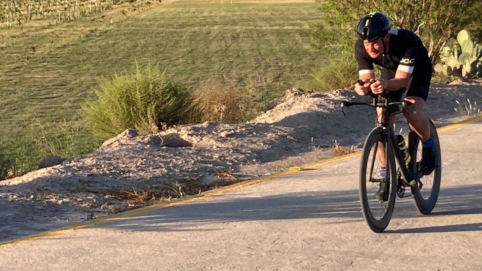 Stuart Gillett in black cycling gear on a black road bike.