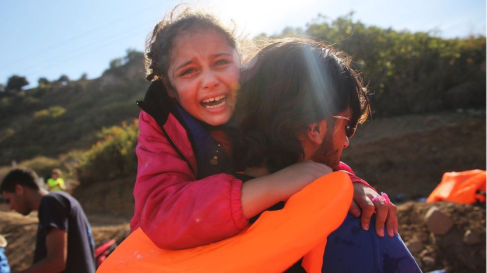 A young girl is helped moments after she arrived with other Syrian and Iraqi migrants on the island of Lesbos in 2015