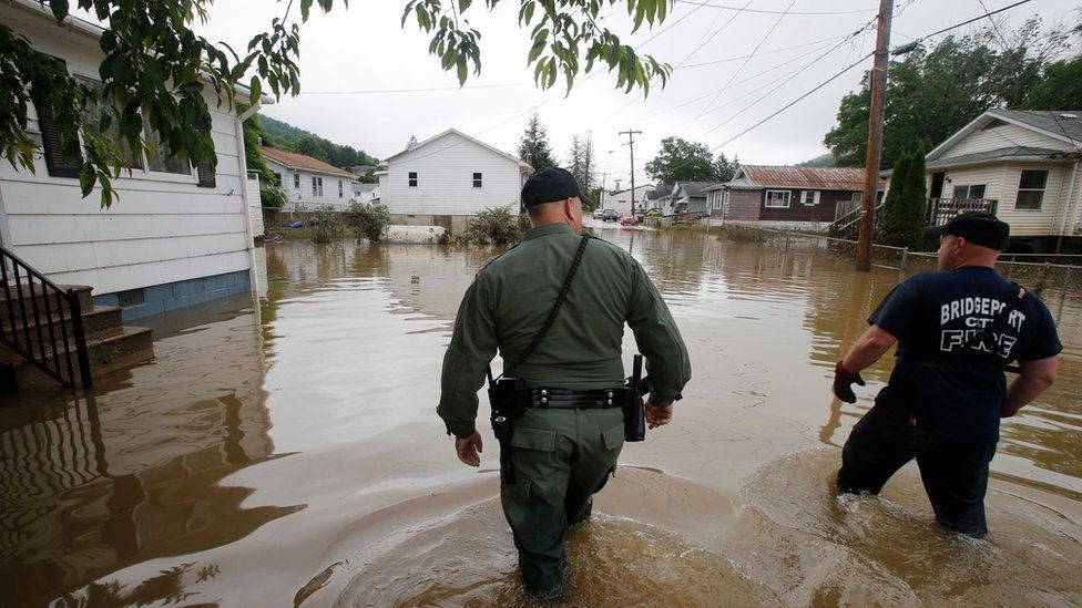 Rescue workers wade through flooded streets as they search homes in Rainelle, West Virginia, on 25 June