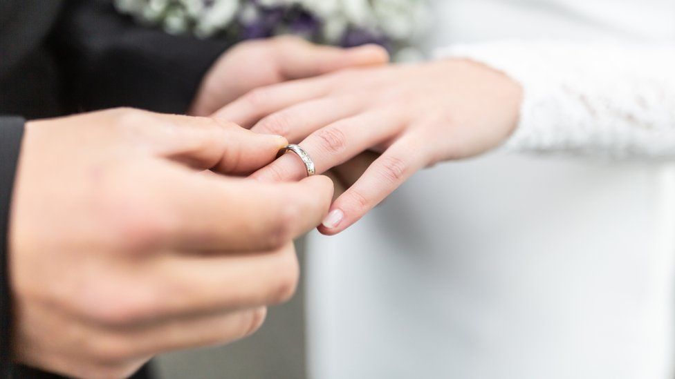 A groom puts a wedding ring on a bride's finger