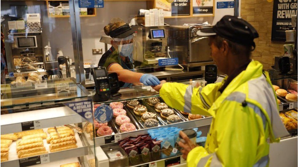 Customer hands over cash to shop worker