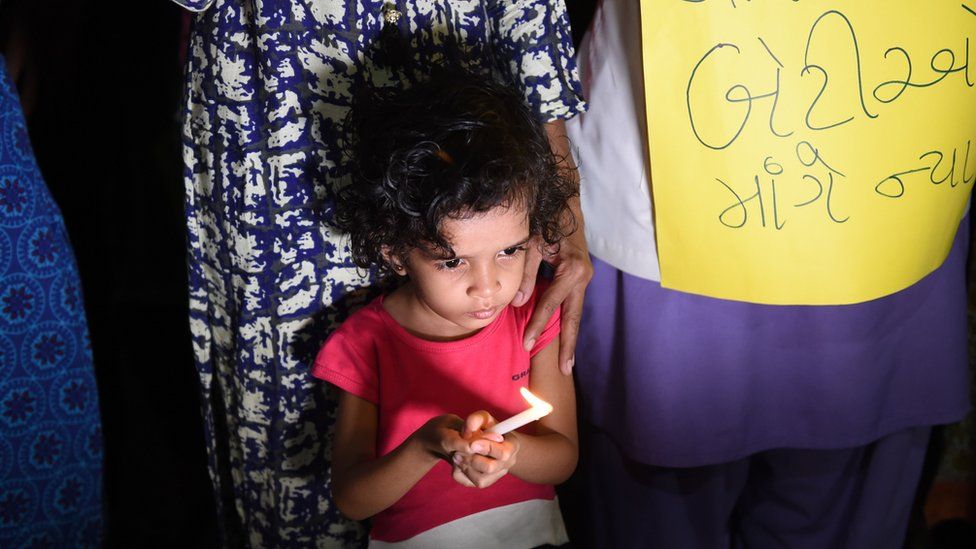 A little girl holds a candle during a candlelight protest in India following high profile rape cases.