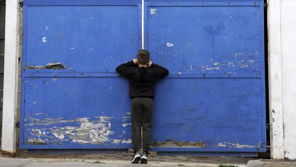 Young fan peers through a gate at Kenilworth Road