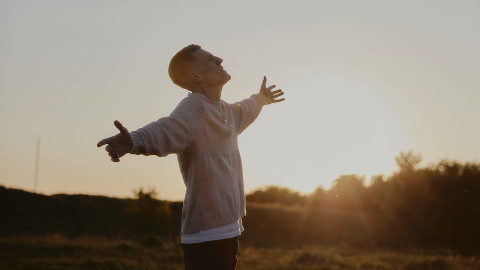 Image of Nathan Evans. He is pictured with his arms out, looking up to the sky.