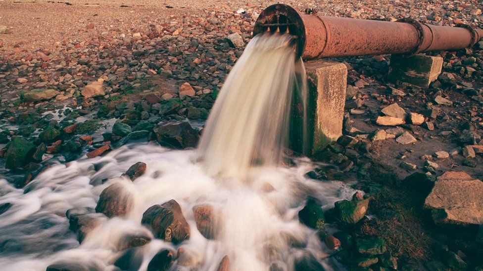 Effluent flowing from a rusty pipe onto a river bank by the River Tyne, Newcastle-upon-Tyne, England.