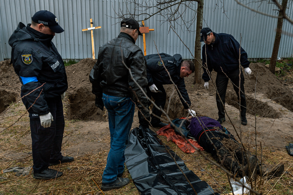 Police in Bucha examine a body unearthed in a field. At least 500 dead have been found since the Russians left.