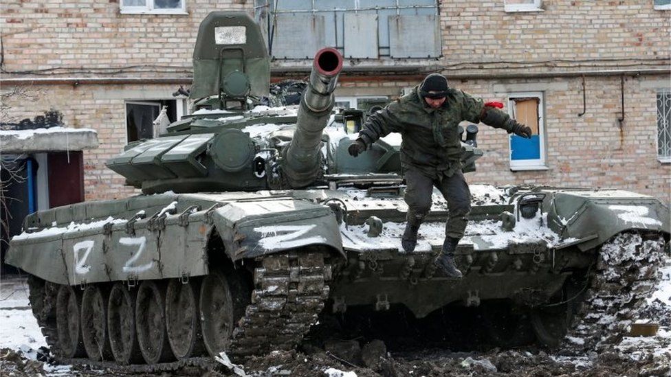 A service member of pro-Russian troops in uniform without insignia jumps off a tank with the letters "Z" painted on it outside a residential building which was damaged during Ukraine-Russia conflict in the separatist-controlled town of Volnovakha in the Donetsk region, Ukraine March 11, 2022.