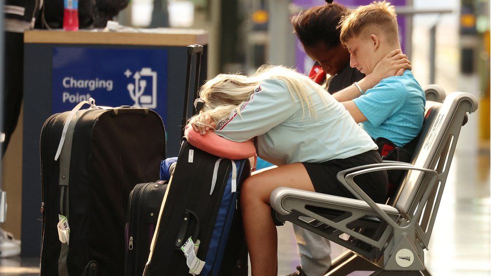 A woman rests her head on her luggage at Manchester Piccadilly Station during the rail strike
