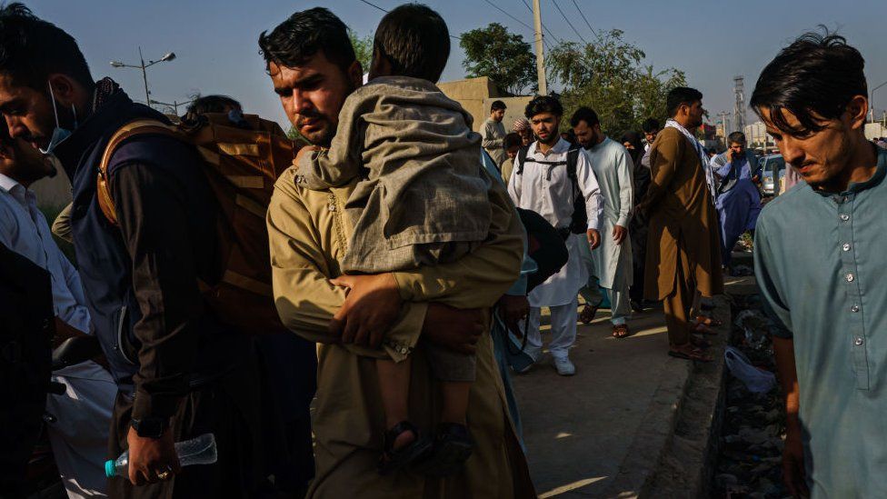 Afghans make their way the road to the military entrance of the airport for evacuations, in Kabul, Afghanistan