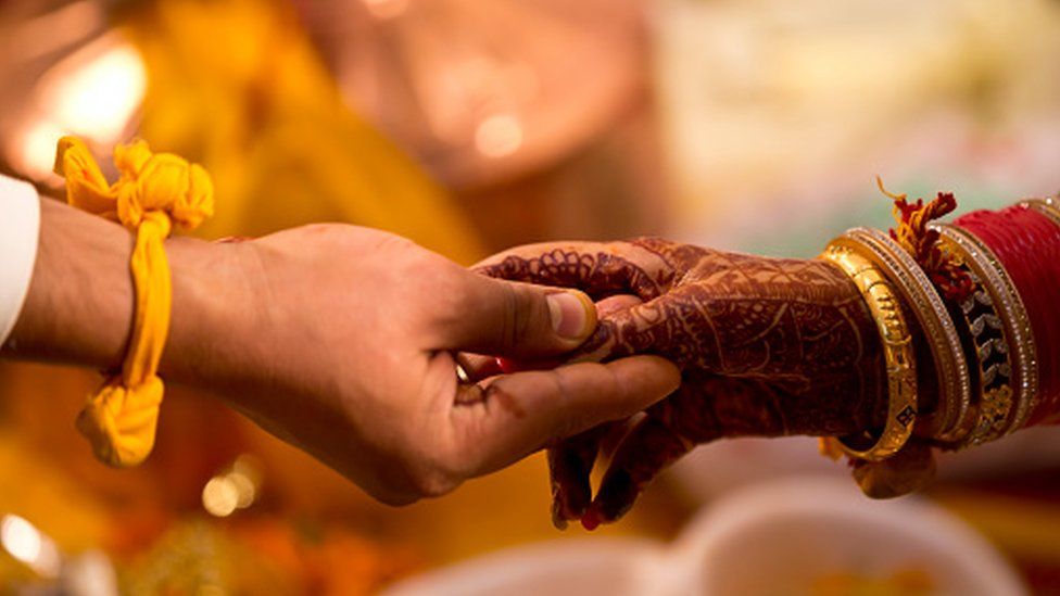 Indian bride and groom holding hands during wedding ceremony