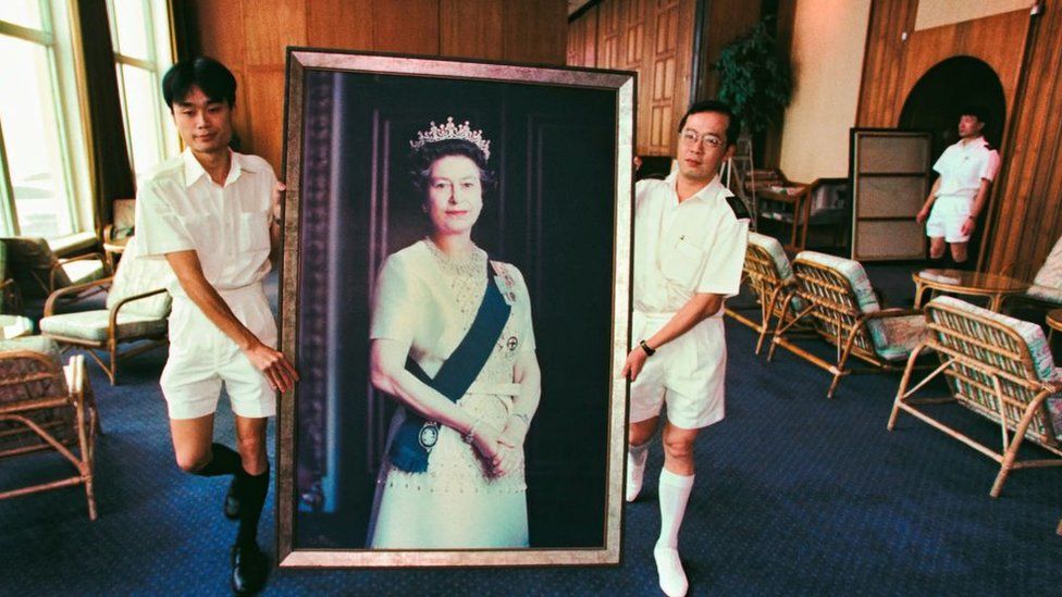 Two Royal Navy sailors carry a portrait of Britain's Queen Elizabeth II for the last time as her picture was taken down from the wall on June 16, 1997