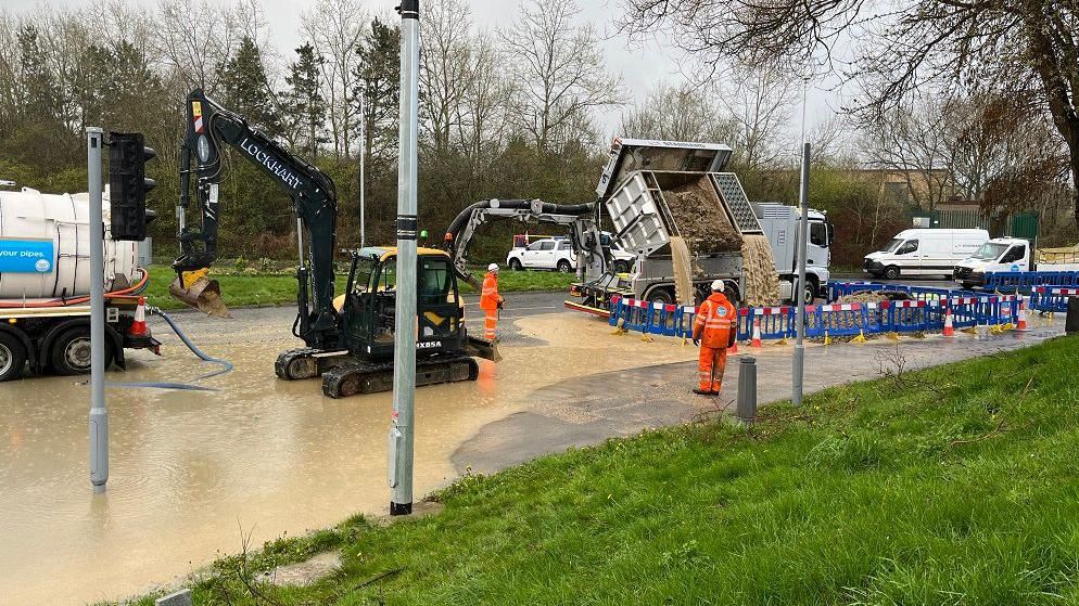 Diggers, water pumps and trucks working on a flooded road
