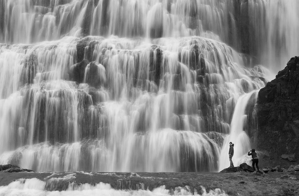 Two figures beside the Dynjandi waterfalls in Iceland