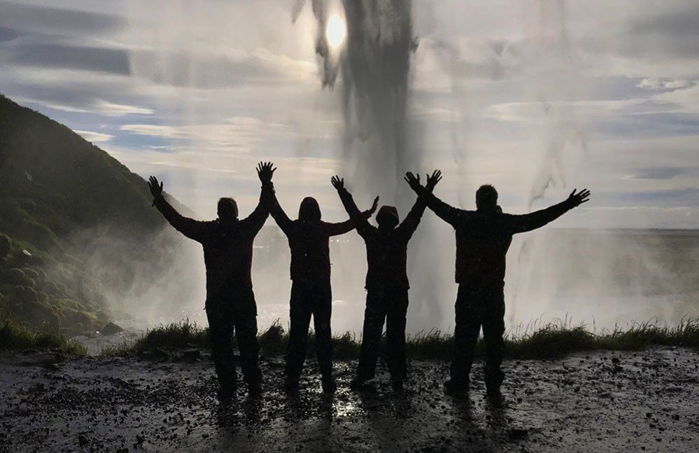 Four people behind a waterfall