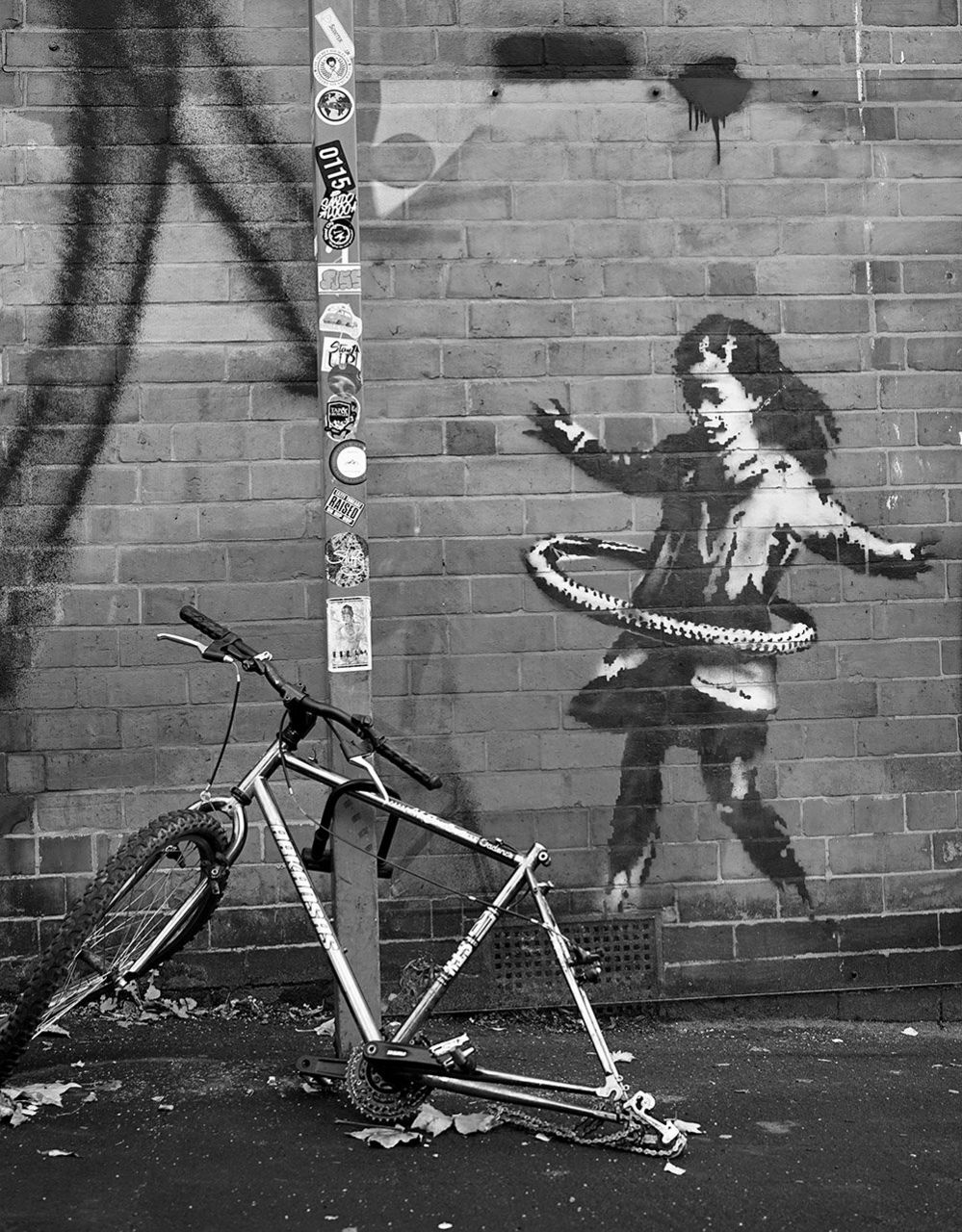 Banksy art on the wall alongside an old bicycle