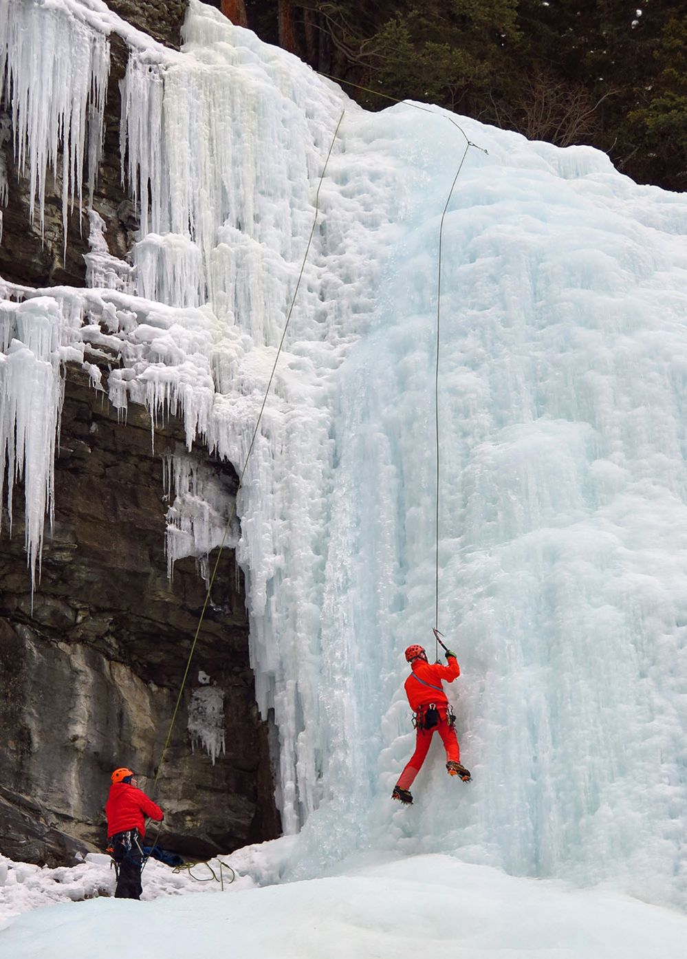 A man climbs a frozen waterfall