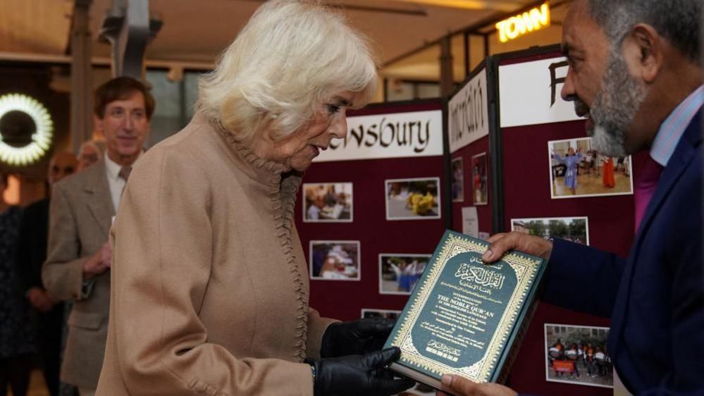A man hands a copy of the Quran to the Queen