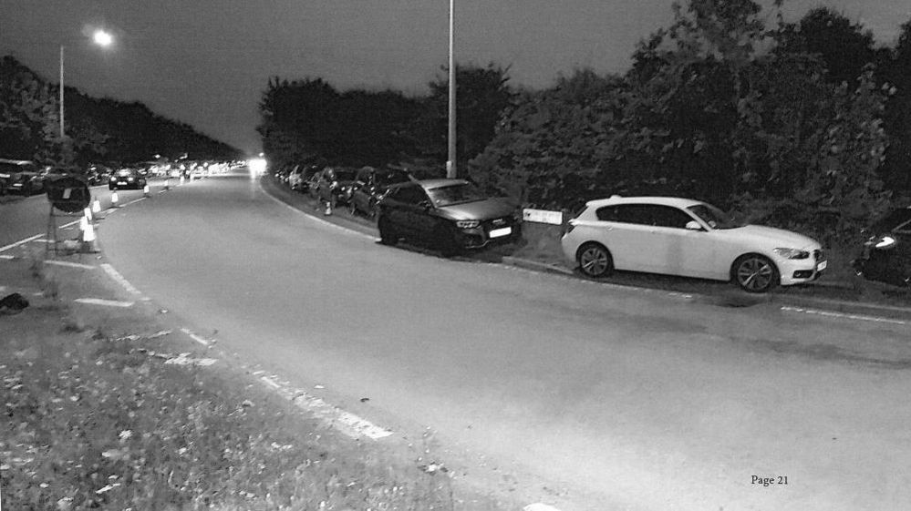 A black and white image of cars parked on the curb on Regiment way in Essex during a festival in September 2021