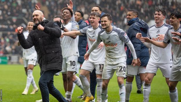 Swansea City players celebrate with head coach Luke Williams